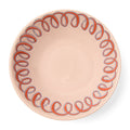 Pink ceramic plate with decorative pattern on a white background
