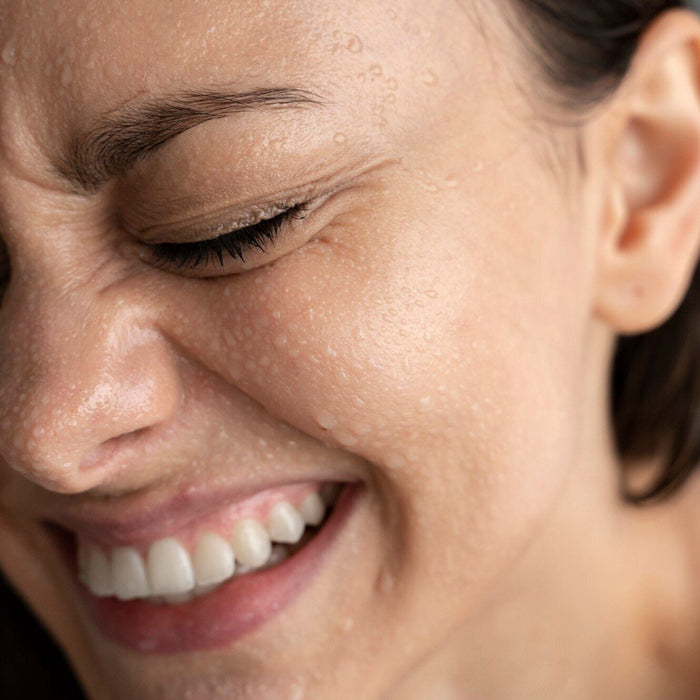 white woman using Boost: A Solution mist on their face for hydration and relief.