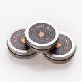 Three stacked tins of Field Company Cast Iron Seasoning Oil on a white background
