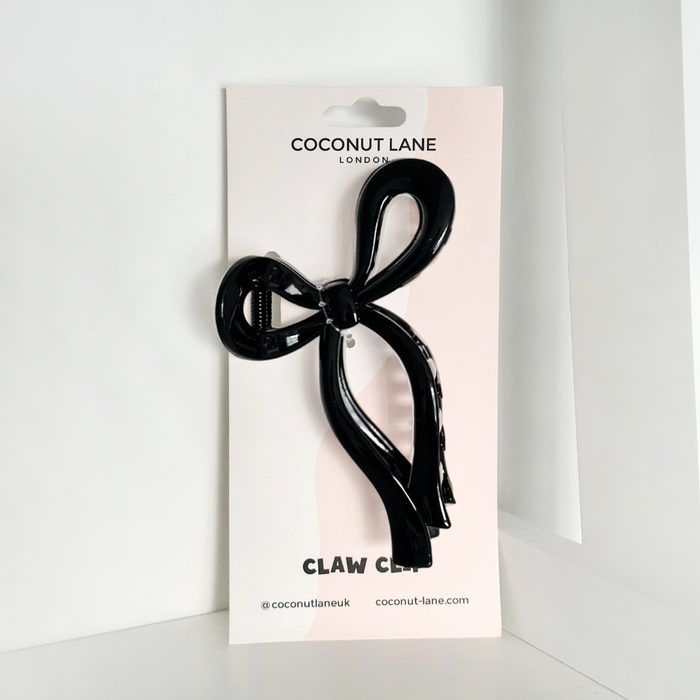 Black bow-shaped claw clip by Coconut Lane on branded packaging, shown upright against a white background.