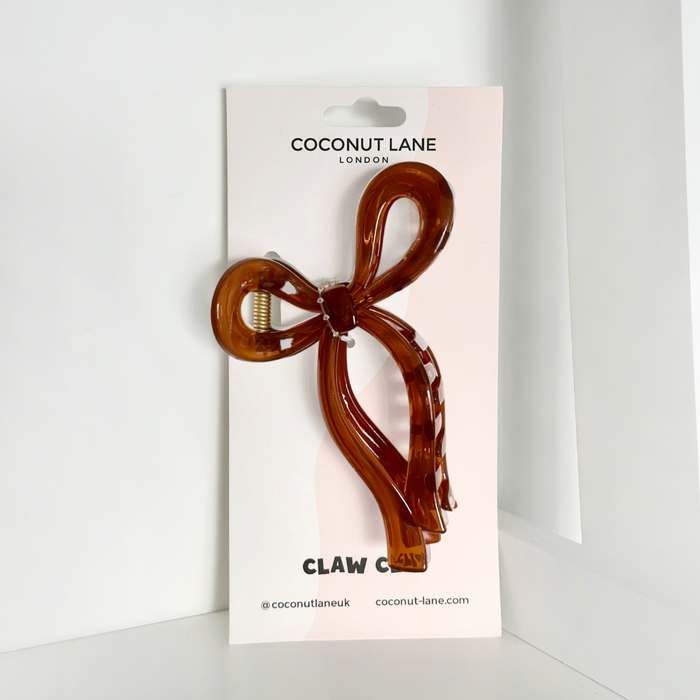 Brown bow claw clip by Coconut Lane, upright on a card with a white background.