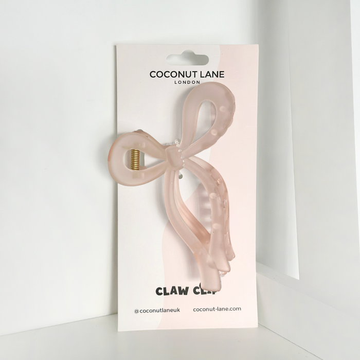 Pink bow-shaped claw clip displayed on a Coconut Lane branded card against a white background.