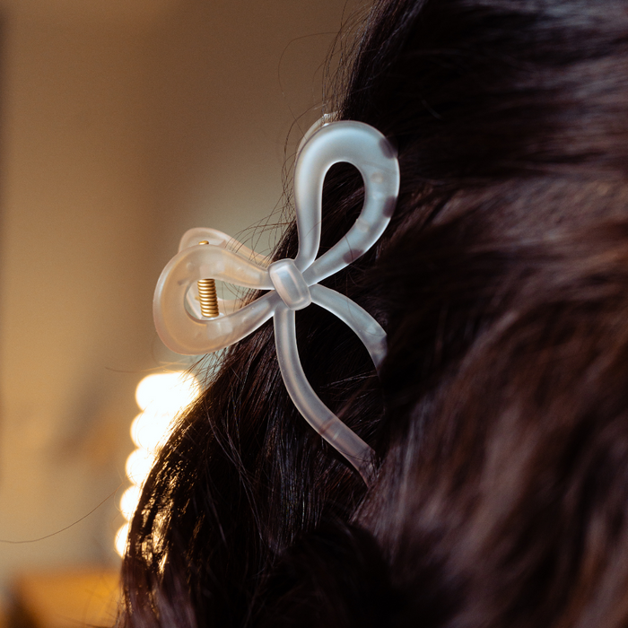White Coconut Lane bow claw clip securing dark hair.