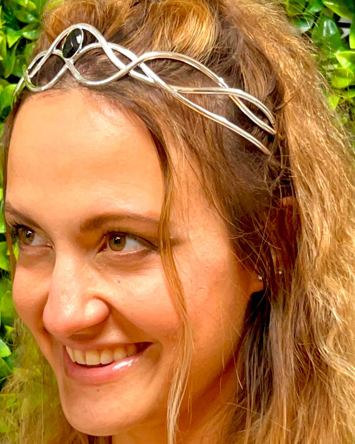 Model wearing silver wire braided crown with interwoven wire design and green gemstone centerpiece, front view.