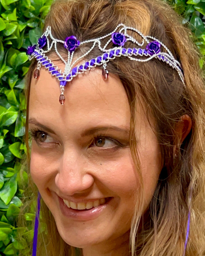 Model wearing Fairy Princess Crown silver ribbon tiara with purple roses and gemstone accents, front view.