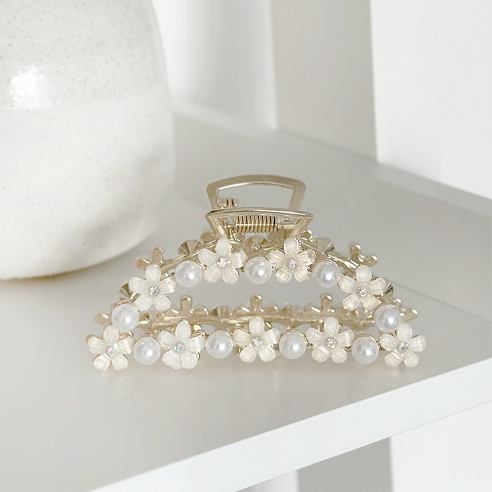 Coconut Lane claw clip with small flower accents, featuring pearls, shown on a white shelf.