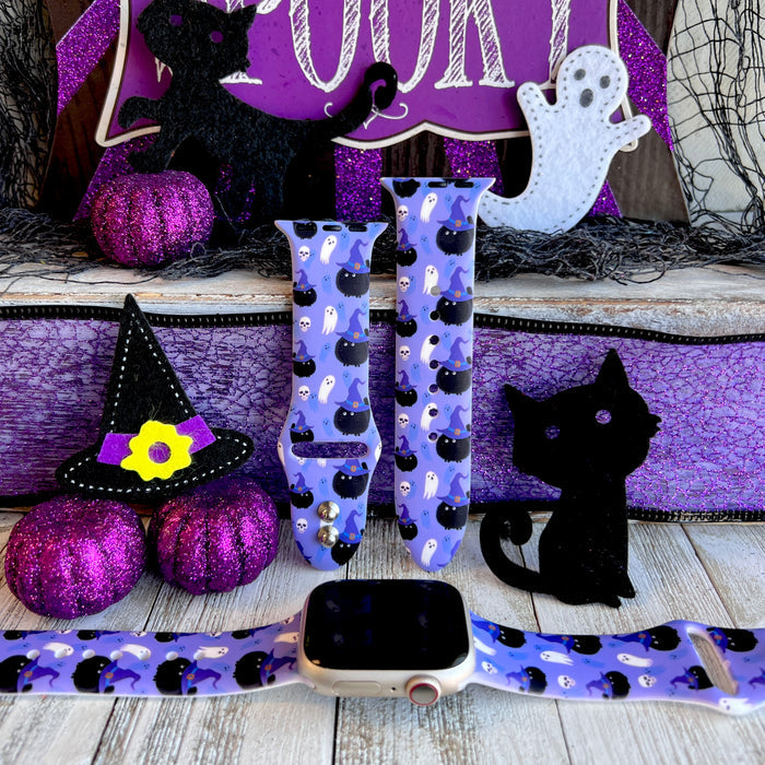 Ghostly Whisker's silicone Apple Watch band hero shot in lavender with black witch-hat cats, white ghosts and mini skulls, shown with a rose gold Apple Watch.