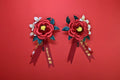 Two red handmade Chanhua bridal boutonnieres with customizable ribbons on a red background