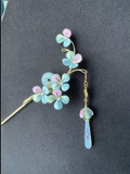 A handmade Chanhua hydrangea - styled hairpin with pastel - colored petals and a tassel