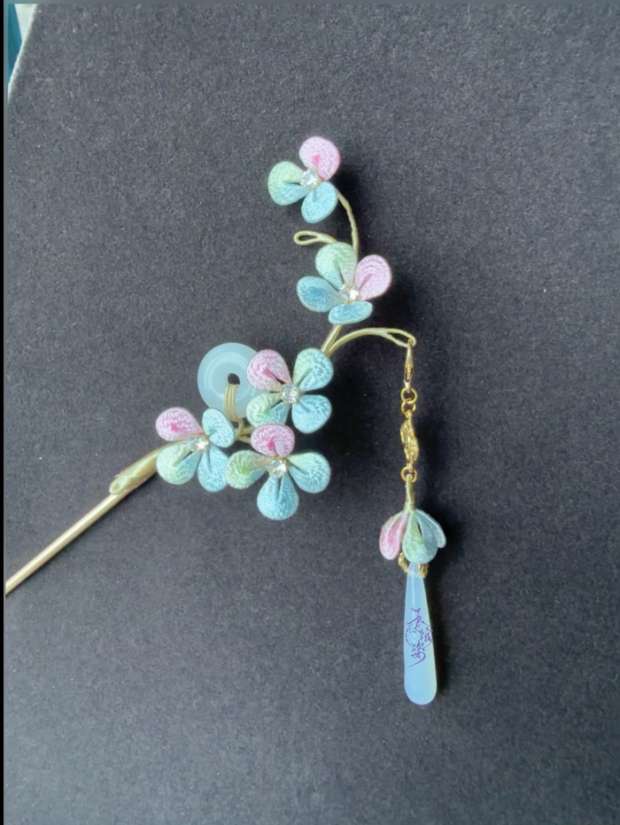 A handmade Chanhua hydrangea - styled hairpin with pastel - colored petals and a tassel