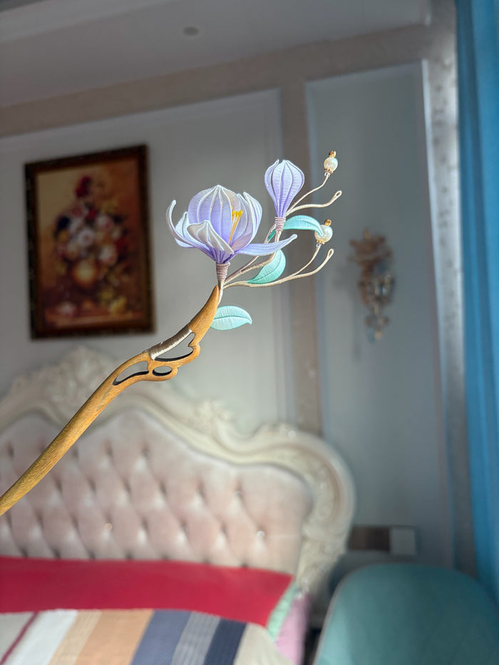 A handmade Chanhua magnolia hairpin with purple flowers and green leaves on a wooden stem.-2