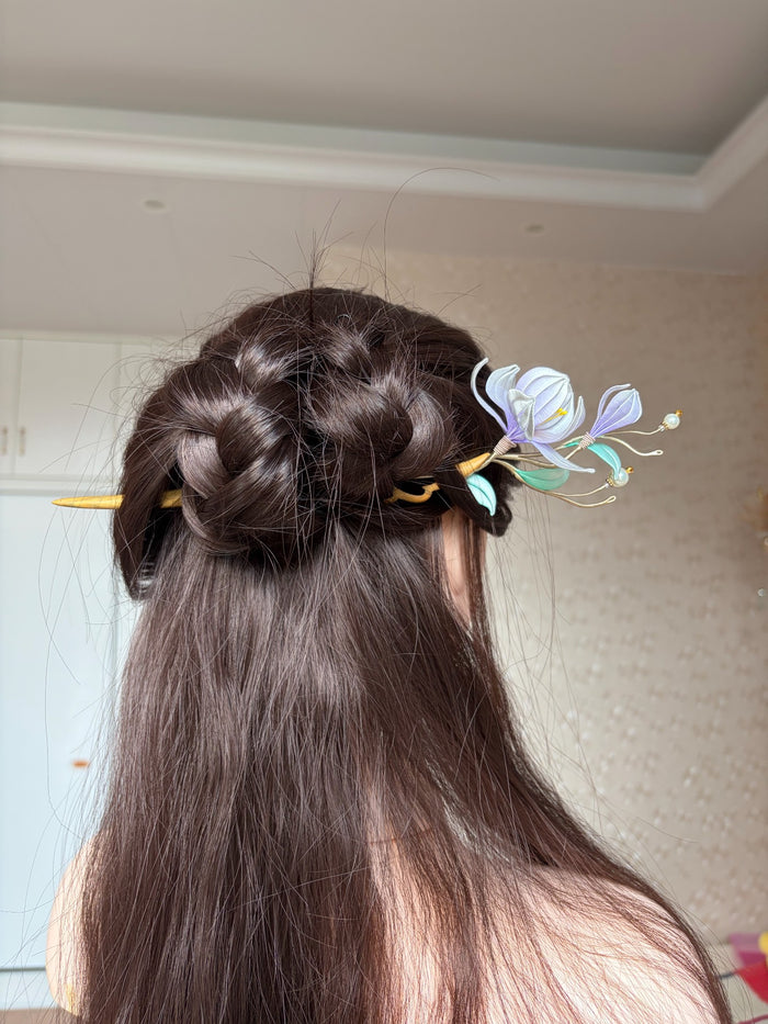 A handmade Chanhua magnolia hairpin with purple flowers and green leaves on a wooden stem.-5