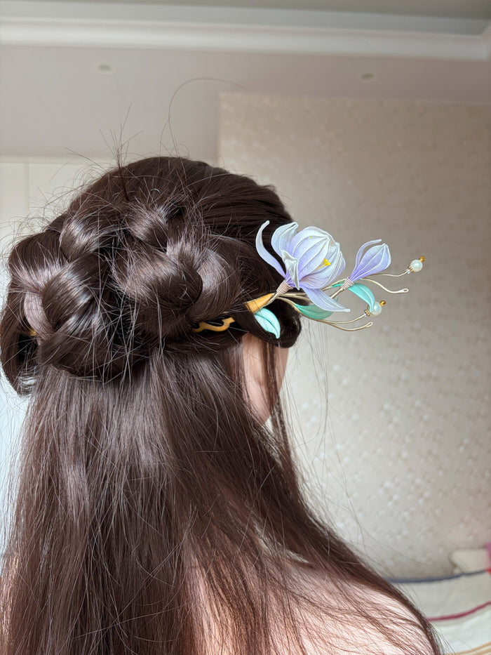 A handmade Chanhua magnolia hairpin with purple flowers and green leaves on a wooden stem.-6