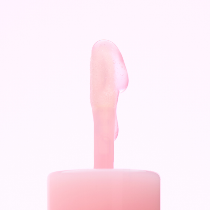 close up of pink applicator of lip gloss with a drop of gloss cascading down side