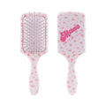 Two views of a paddle hairbrush with a white body decorated with pink strawberry patterns. One view shows the bristle underside with metal pins, and the other shows the back with the brand name 'Mare' and 'LEVENSHACKS' in pink script.