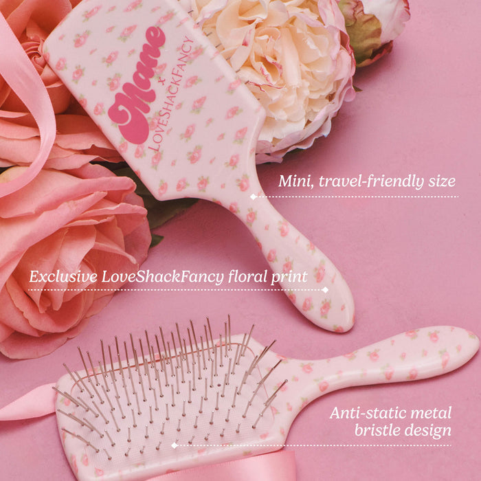 Two floral hairbrushes on a pink background with roses. One brush is larger and reads 'Mome x LoveShackFancy' with the phrase 'Mini, travel-friendly size.