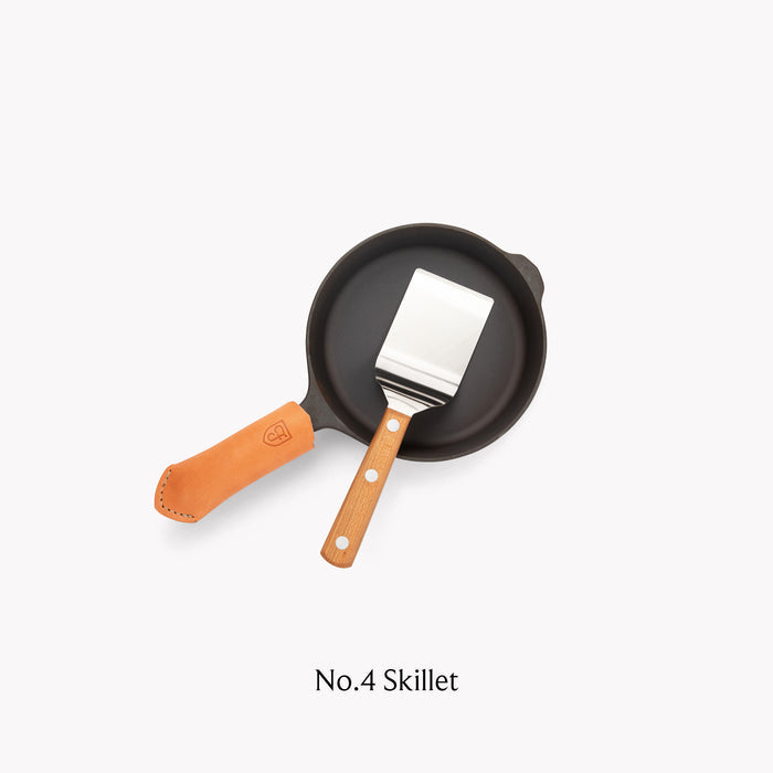 Field Mini Turner resting in a No.4 Skillet with tan leather handle cover, overhead view