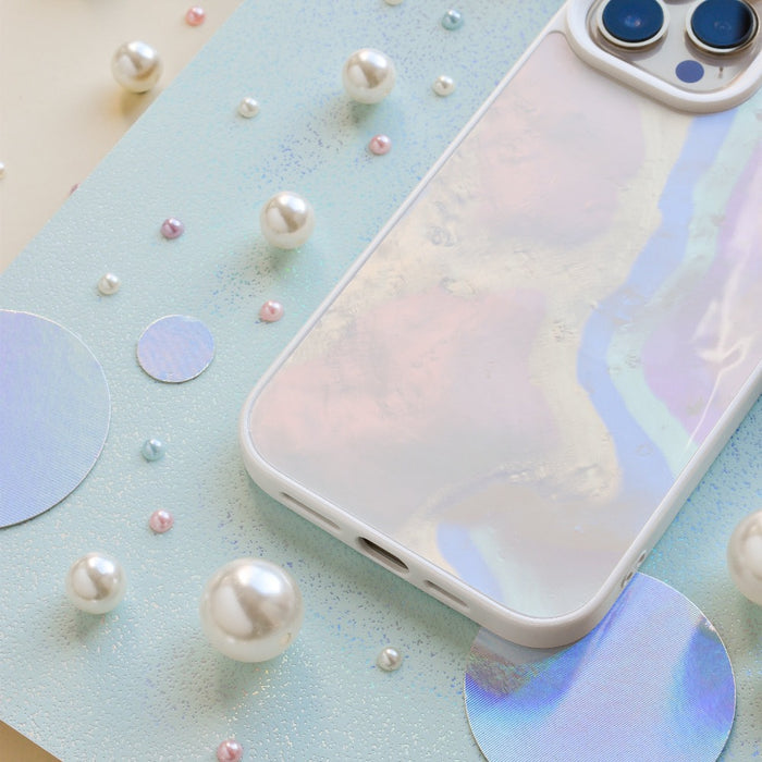 A pastel-colored smartphone with Coconut Lane's Mother of Pearl Phone Case lies on a light blue background adorned with various sizes of glossy white and pastel-colored beads and circular holographic cutouts.