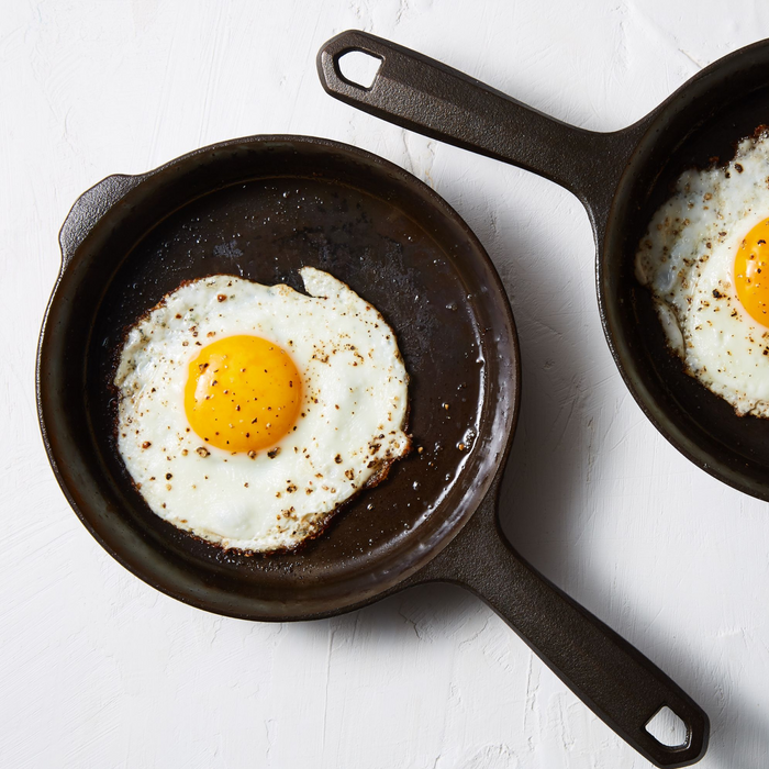Fried eggs cooking in two No.4 Field Cast Iron Skillets, overhead view