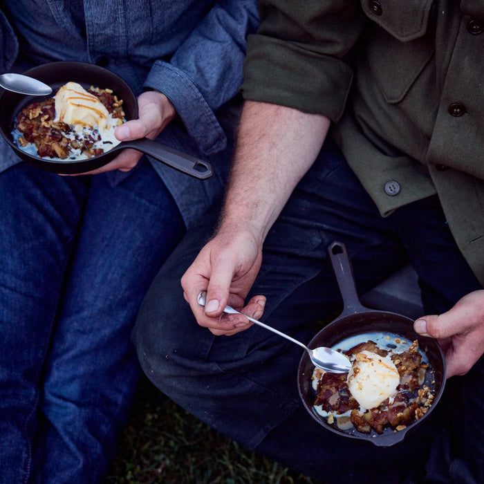 Two people eating fruit crisp with ice cream from No.4 Field Cast Iron Skillets outdoors