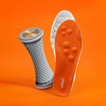 A textured grey foot roller and an orange insole floating on an orange backdrop.