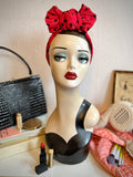 Mannequin head with red polka dot headband on a table.