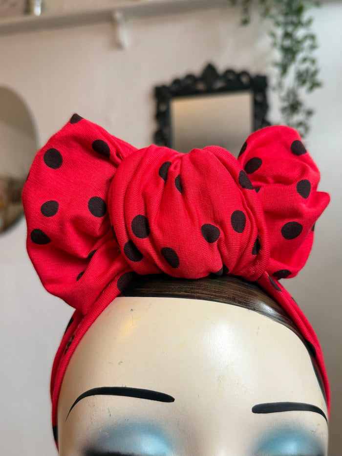 Mannequin head wearing a red polka dot turban with a neutral background