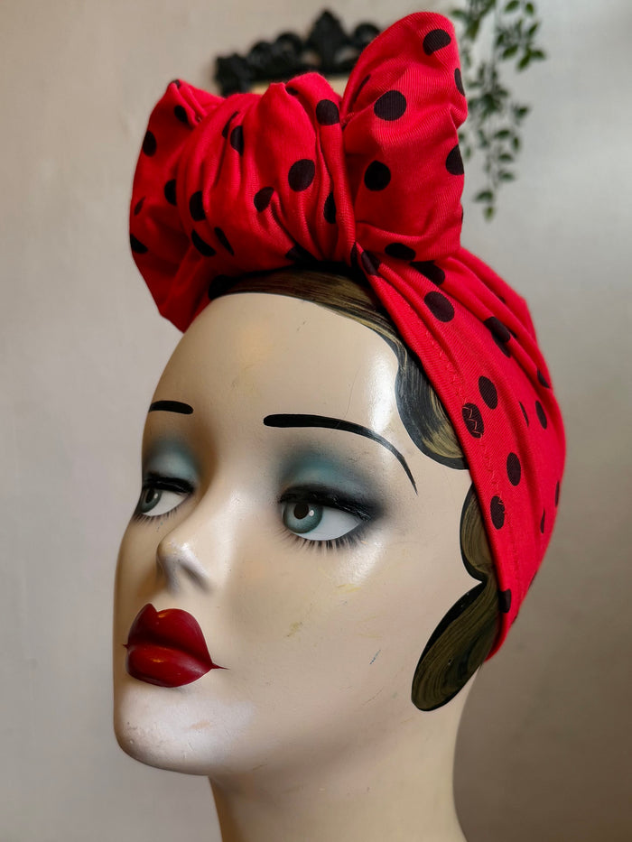 Mannequin head wearing a red polka dot turban with a neutral background
