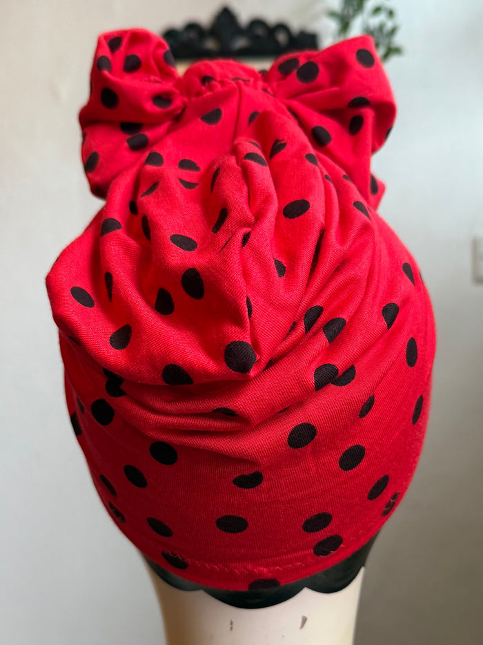 Mannequin head wearing a red polka dot turban with a neutral background