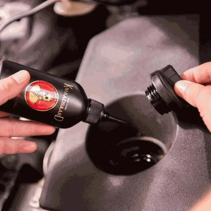 Rooibaard Kwaadbaard Sauce bottle being opened and held close to a container, showcasing its packaging and design.