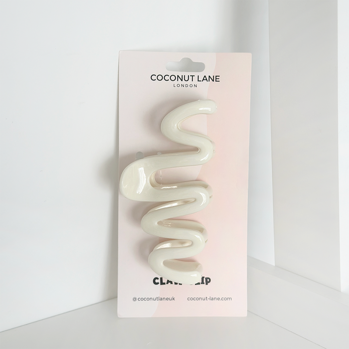Cream-colored squiggle-shaped claw hair clip with a smooth finish by Coconut Lane.