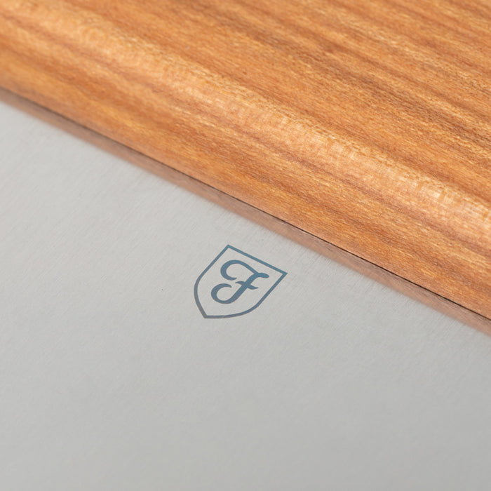 Close-up of the Field Bench Scraper's stainless blade with shield logo and cherry wood handle