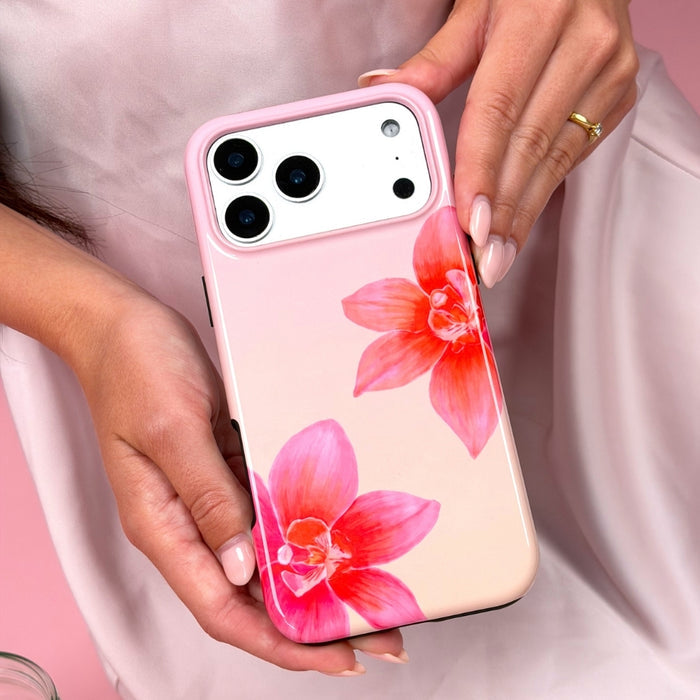 Phone case with pink orchid floral design held by a person against a light pink background
