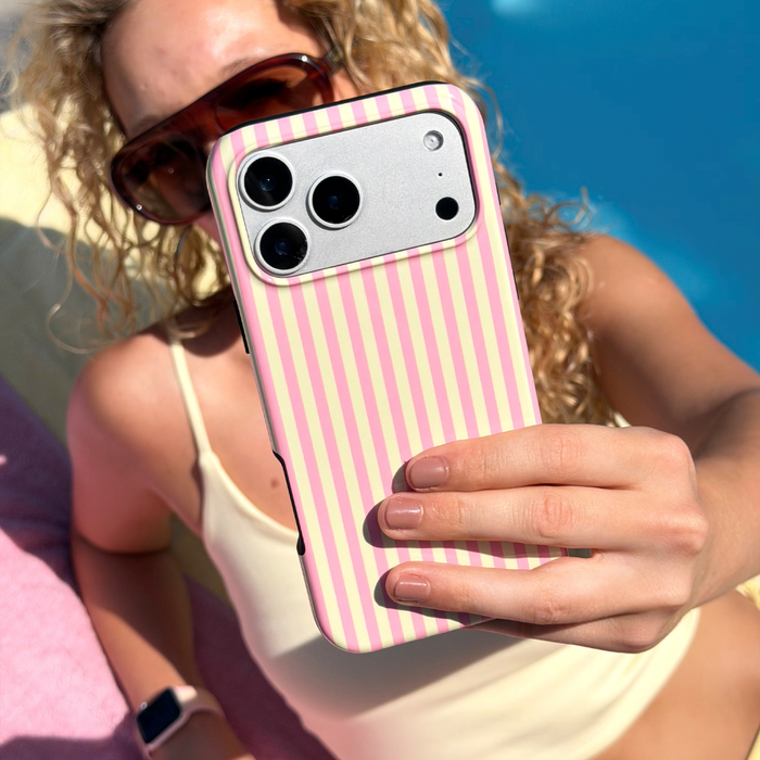 Person holding a phone with a pink and yellow striped case by a pool