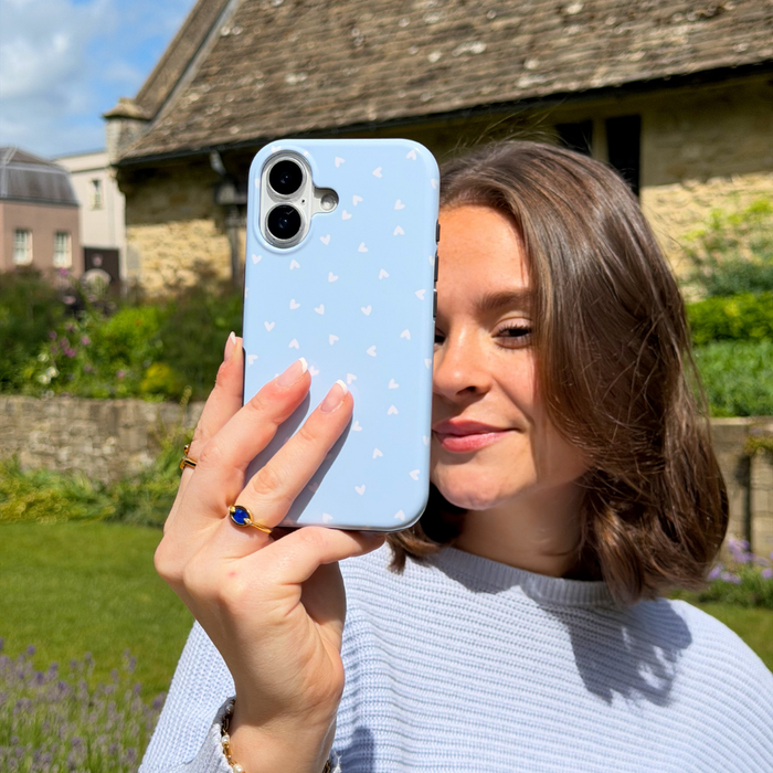 Girl posing with her Tough MagSafe Blue Hearts Phone Case in a pretty garden