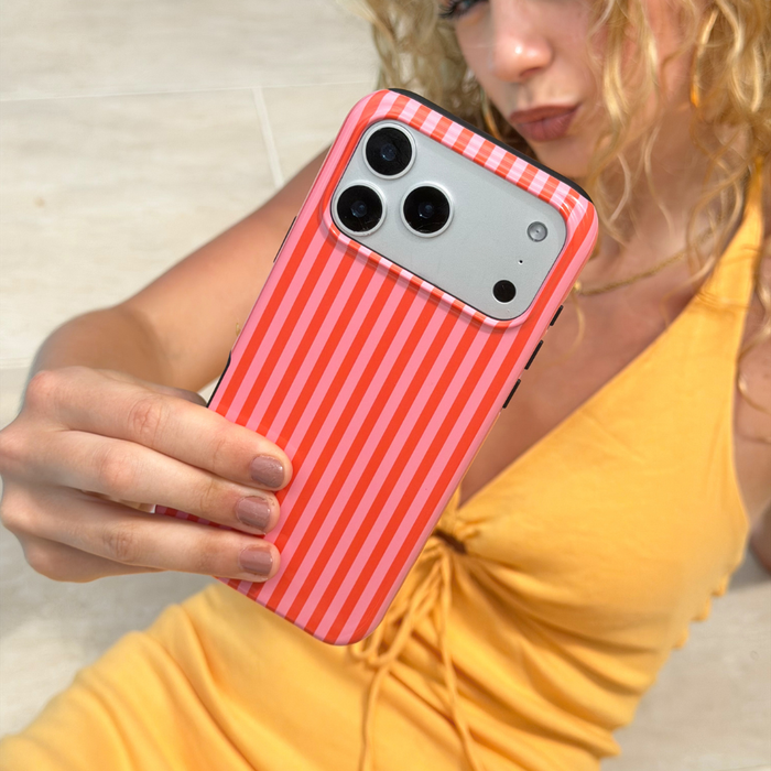 Person holding a phone with a orange and pink striped case