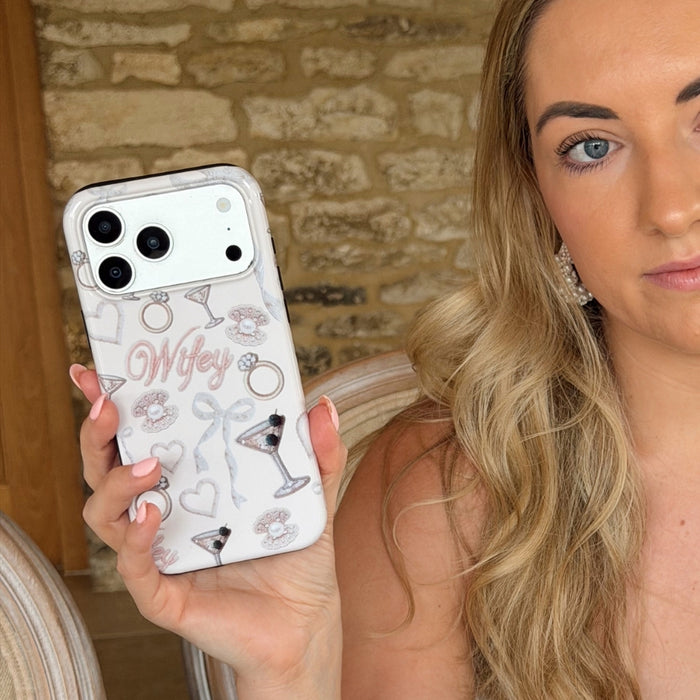 Woman holding a phone with a decorative case featuring the word 'Wifey' and other designs.
