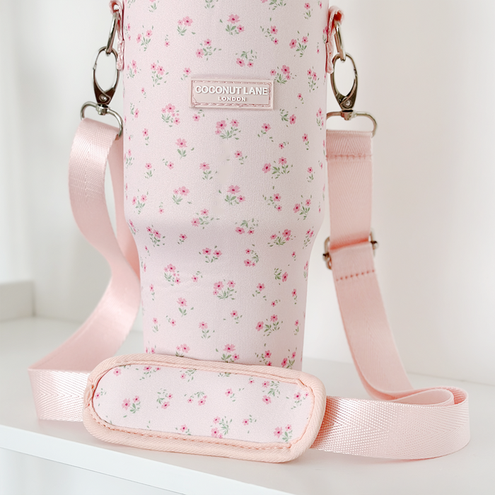Pink tumbler carry case with small floral pattern, adjustable strap, and Coconut Lane label on the front.