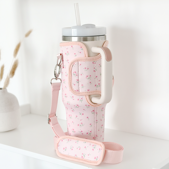 Stanley Quencher 40oz in a pink floral Coconut Lane carry case with handle and strap, sitting on a white shelf.