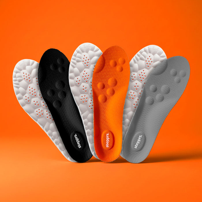A textured grey and gold foot massage roller floating on an orange backdrop