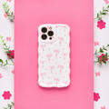 Wavy phone case with small bows, pink flowers, and green leaves on a pastel background.