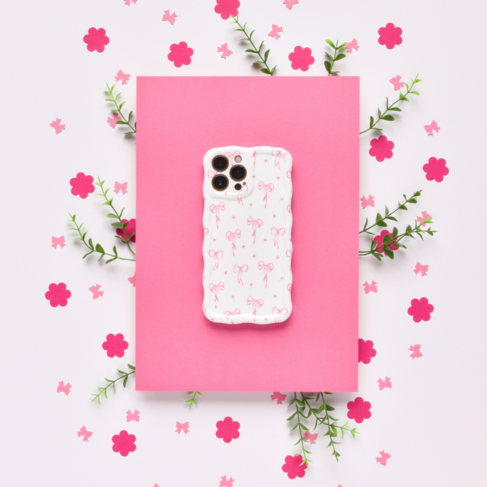 Pink wavy phone case with dainty bow pattern, small bows, paper flowers, and green leaf accents.
