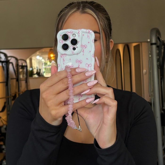 Woman with light pink nails holds a Coconut Lane wavy phone case with a dainty bows pattern.