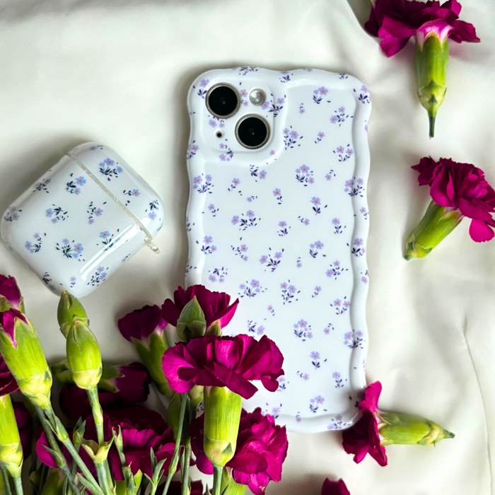 Periwinkle Wavy Phone Case with ditsy floral pattern, displayed on white fabric with pink carnations.