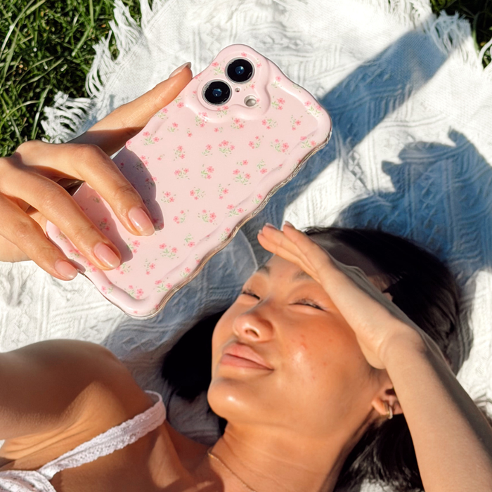 Girl at a picnic with flowers holding her Wavy Ditsy Floral Phone Case