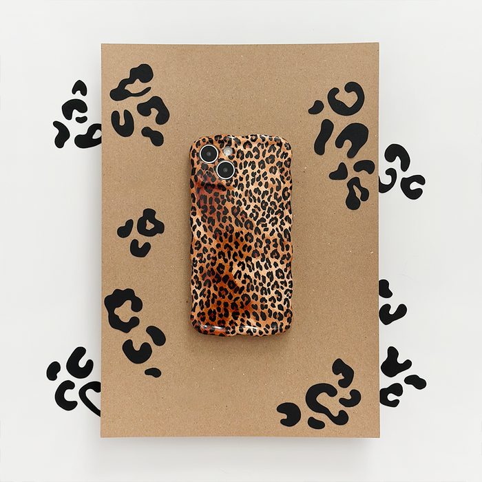 Leopard print wavy phone case by Coconut Lane displayed on a brown board with black leopard spots.