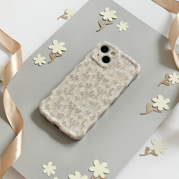 Coconut Lane wavy phone case with nude flower pattern on gray background, next to paper flowers and a satin ribbon.
