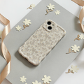 Coconut Lane wavy phone case with nude flower pattern on gray background, next to paper flowers and a satin ribbon.