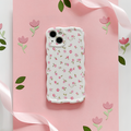 Pink phone case with wavy edges and watercolour flower pattern, displayed with a satin ribbon on a pink background.