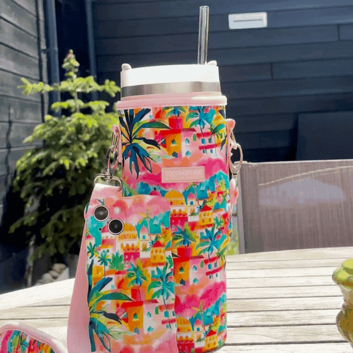 Wavy pastel Coconut Lane phone case and multicolored water bottle on a sunlit outdoor table.